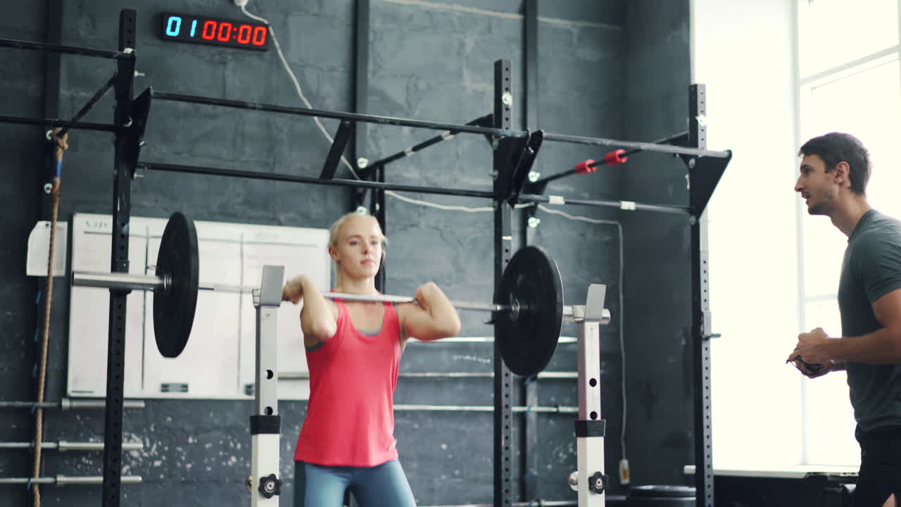체육관 에서 개인 트레이너 와 함께 웨이트 리프팅 하는 여자