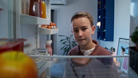 niño adolescente mirando dentro del refrigerador