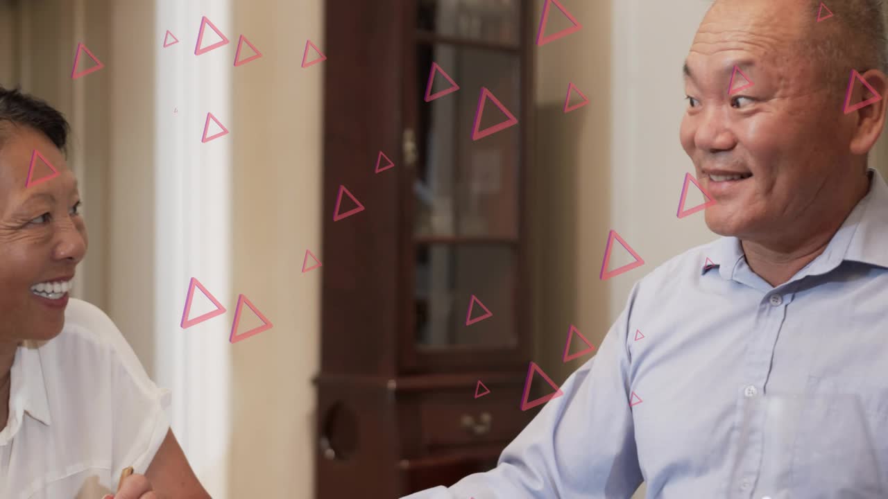 Woman looking right sharing food with chopsticks panning revealing man pink triangles overlaying