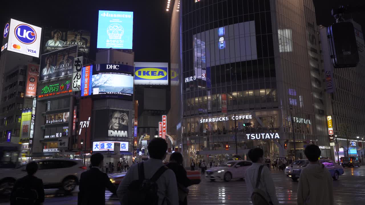 gente esperando en el famoso shibuya scramble durante la noche lluviosa en tokio - tiro estático