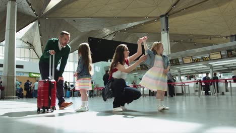 mother and father with two children are sitting in the hall airport. pretty mom is playing with younger daughter. cinematic shot on red camera.