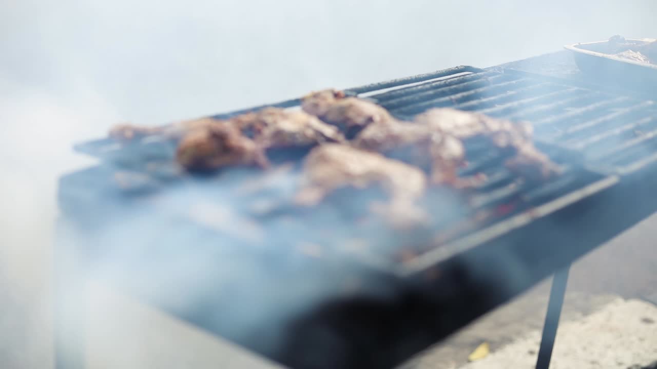 연기가 자욱한 그릴에서 아얌 바카르를 요리하는 아시아 노점상의 슬로우 모션 샷