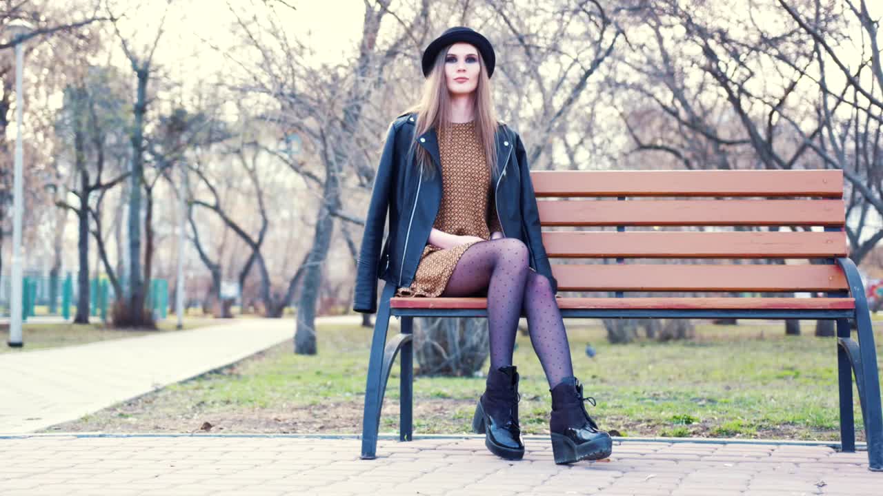 mujer elegante sentada en un banco del parque