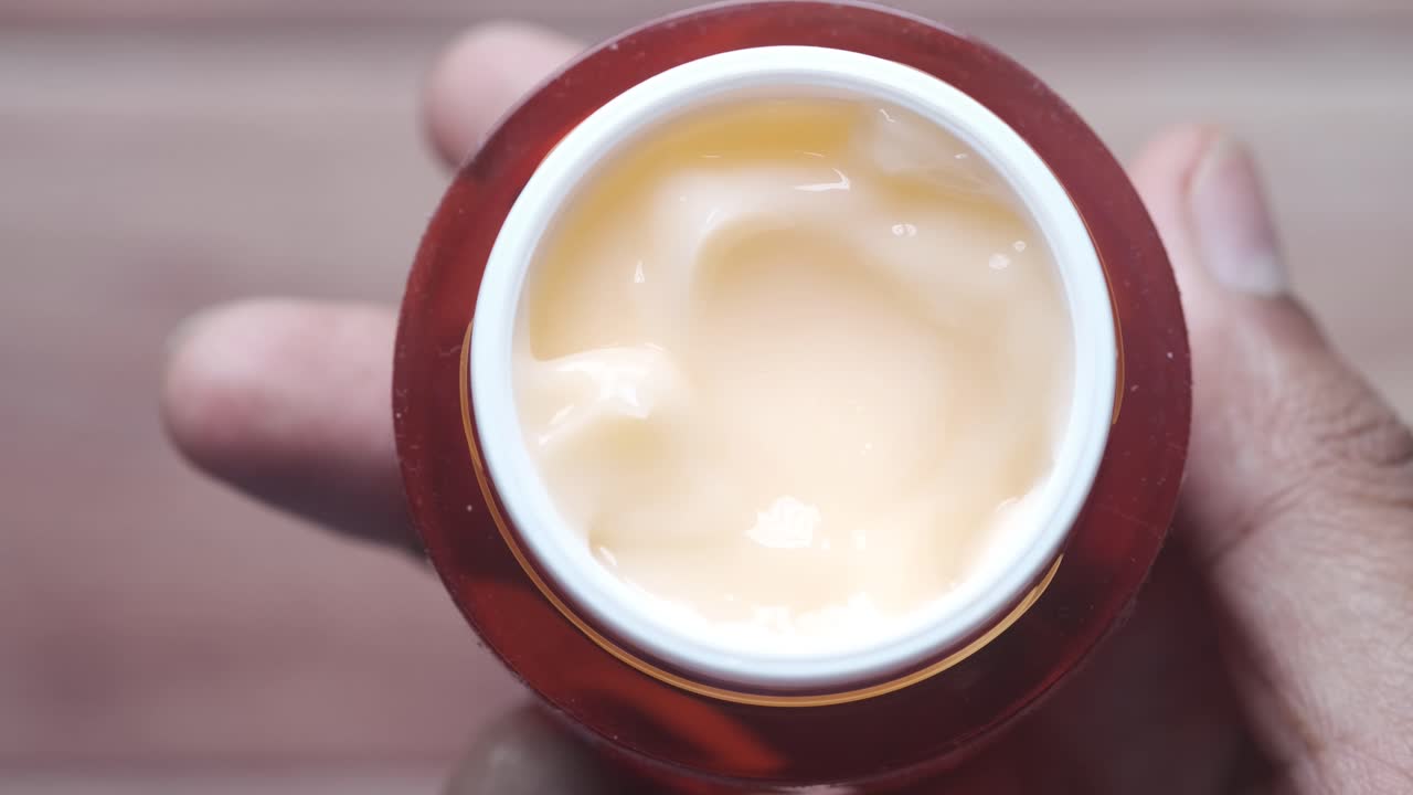 Mano sosteniendo un tarro de crema facial