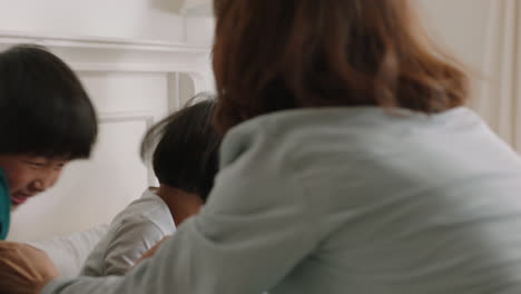 행복한 아시아 가족과 아이들이 침대에 뛰어들고 엄마와 아빠와 함께 놀고 주말 아침에 재미를 느끼고 흥분된 어린 아이들이 부모와 함께 집에서 게임을 즐기고 있습니다. 4k 영상