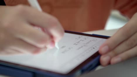 hands of a person writing on a tablet