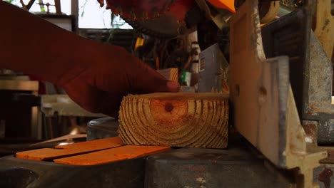 cutting a wooden bar using a mechanical saw