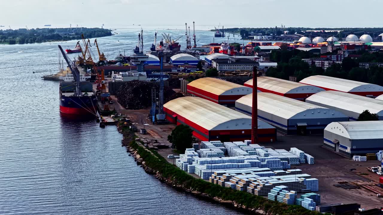 Drone establishing of busy shipping port with cargo containers and docked ships, tracking pan left