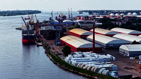 drone establishing of busy shipping port with cargo containers and docked ships, tracking pan left