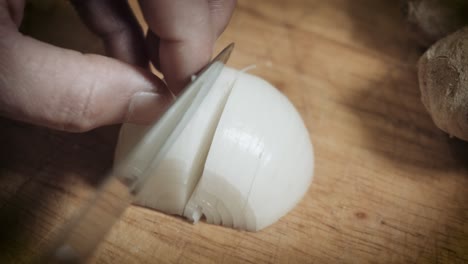 Person-Chopping-White-Onion-Using-Sharp-Kitchen-Knife-Into-Wooden-Chopping-Board