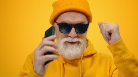 Senior-man-listening-music-in-studio.-Cheerful-guy-dancing-with-phone-indoors.