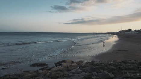 Ruhiger-Strand-Mit-Sonnenuntergang-Und-Allein-Gehender-Person