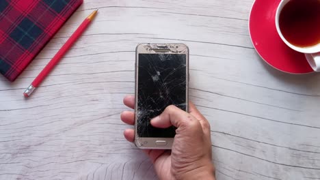 broken smartphone on wooden table with teacup