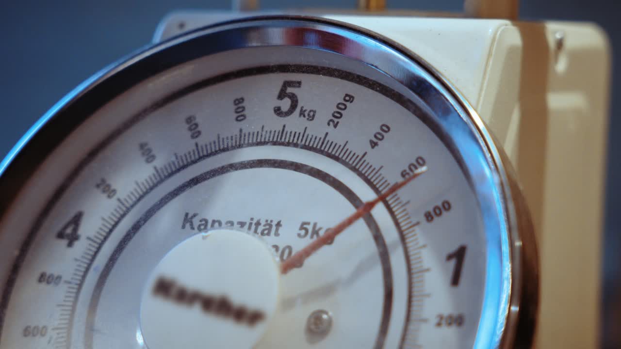 The pointer of a food-weighing scale moves across the dial, a symbol for weight control.