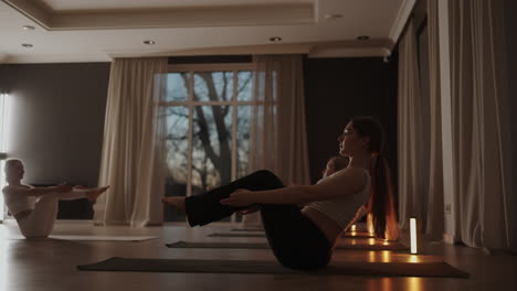 group of young woman practicing yoga with the help of an instructor. they are doing seated side twist asana. in a bright room.