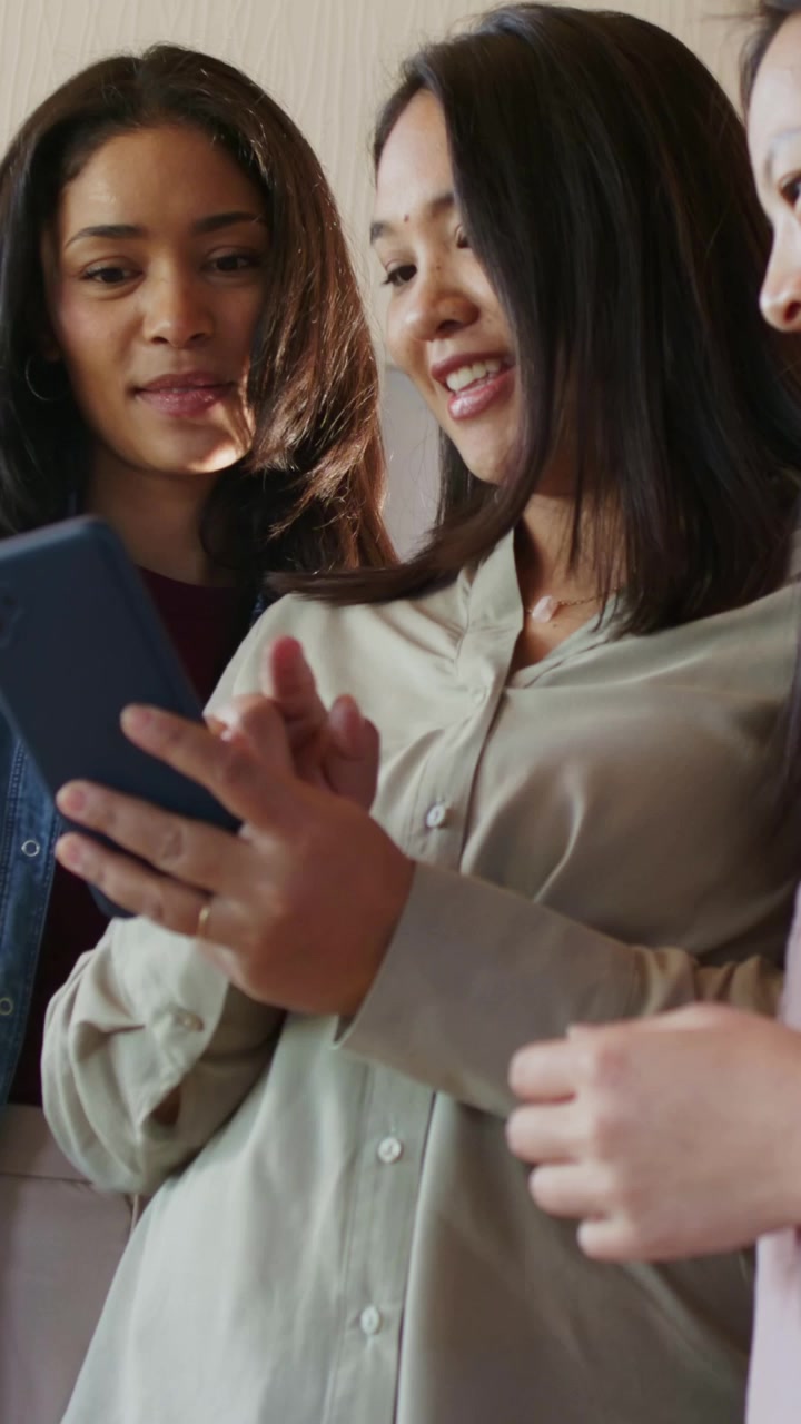 Vertical video: Holding phone center woman beige top tapping screen at home sharing with friends