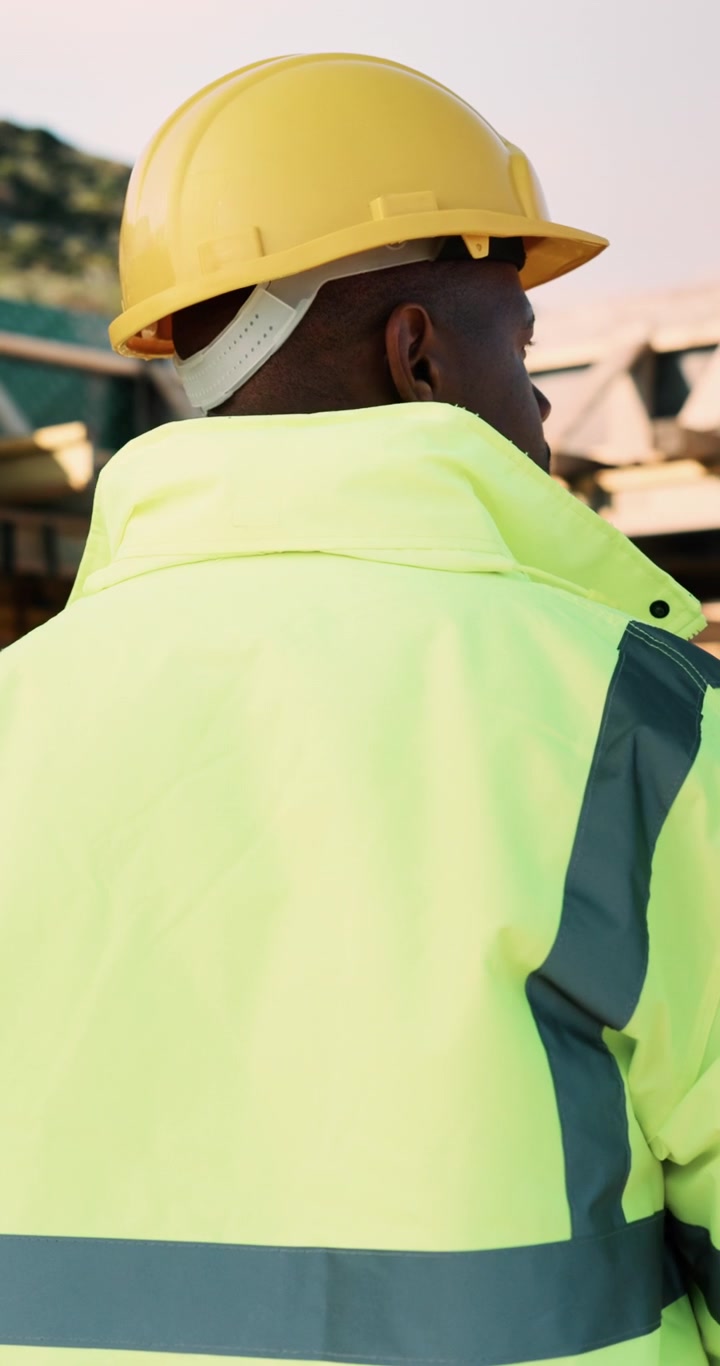 Obrero de construcción poniéndose un casco amarillo en la obra
