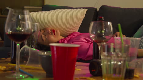 Close-Up-Of-Woman-Lying-Passed-Out-On-Sofa-After-Drinking-Alcohol-At-House-Party-Suffering-With-Hangover-2