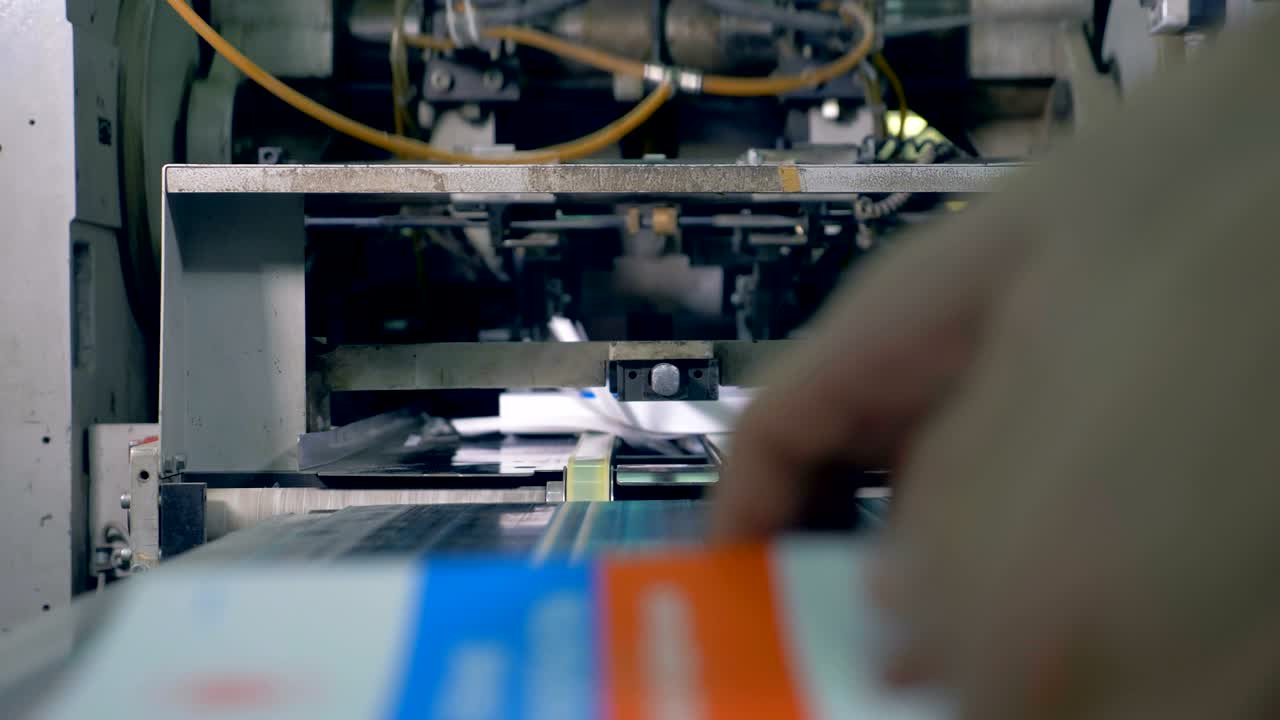 Many books move on a line in a typography facility, close up.