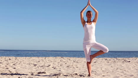mujer practicando yoga en la playa