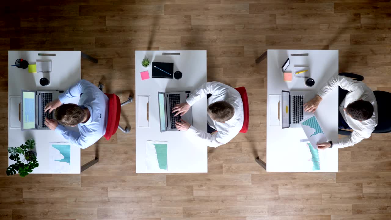 Three young businessman are working on laptops, pass and watch diagrams, work concept, office concept, communication concept, top shot