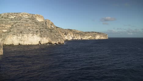 panoramic view of blue grotto sea caves with waves of mediterranean sea crashing on slopes