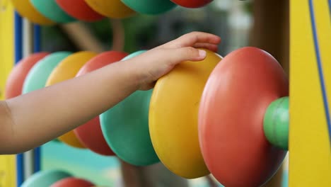 mano de niño jugando equipo de juguete de ábaco colorido en el patio de recreo