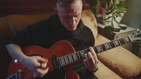man playing vintage guitar at home