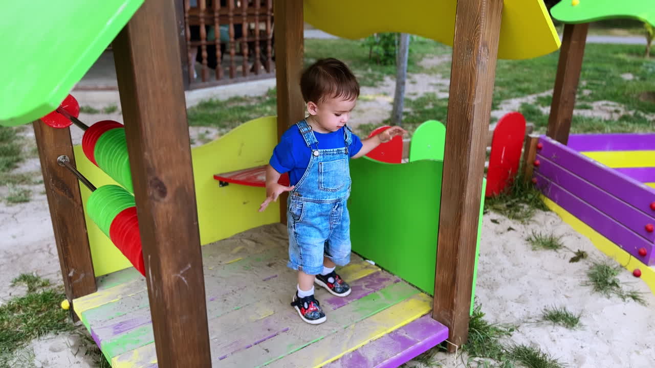 Adorable lovely toddler playing in the wooden house. Baby boy playing with sand on the playground.