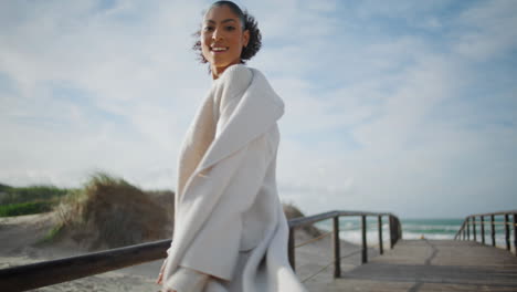 inspired woman running pier in sunlight rear view. happy black hair model turn