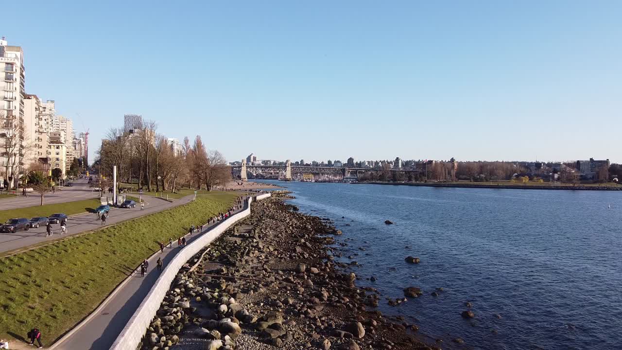 항구의 개인 고급 호텔 옆에 바위와 주거용 건물이있는 푸른 바다 해안으로 조수가 낮은 바다 쪽 해변 지역에서 봄을 걷는 사람들 na1-2