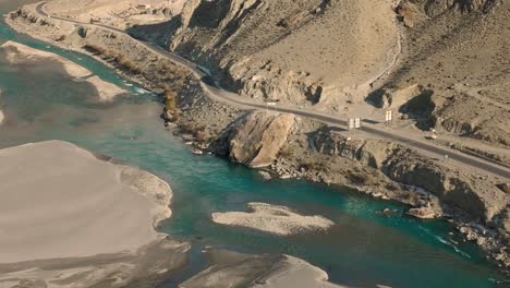 turquoise ghizer river flowing through forest in gahkuch, surrounded by hindu kush mountain range