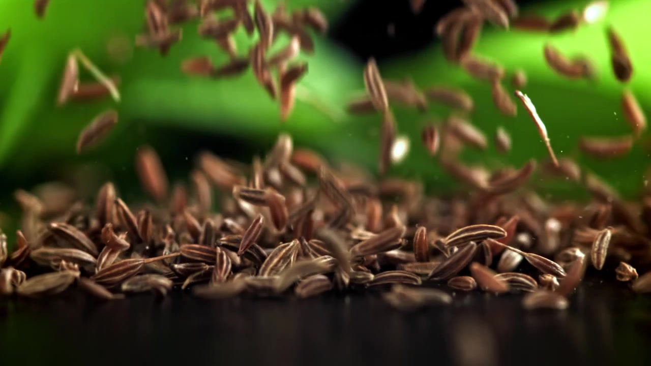 Cumin Seeds Falling in Slow Motion with Green Background