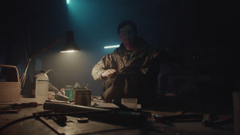 a bombmaker assembles a bomb in his workshop at night