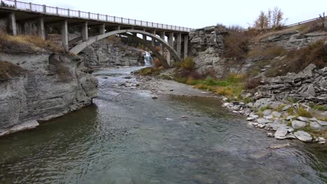 slow motion aerial shot approaching an old arch bridge near lundbreck falls in southern alberta, canada