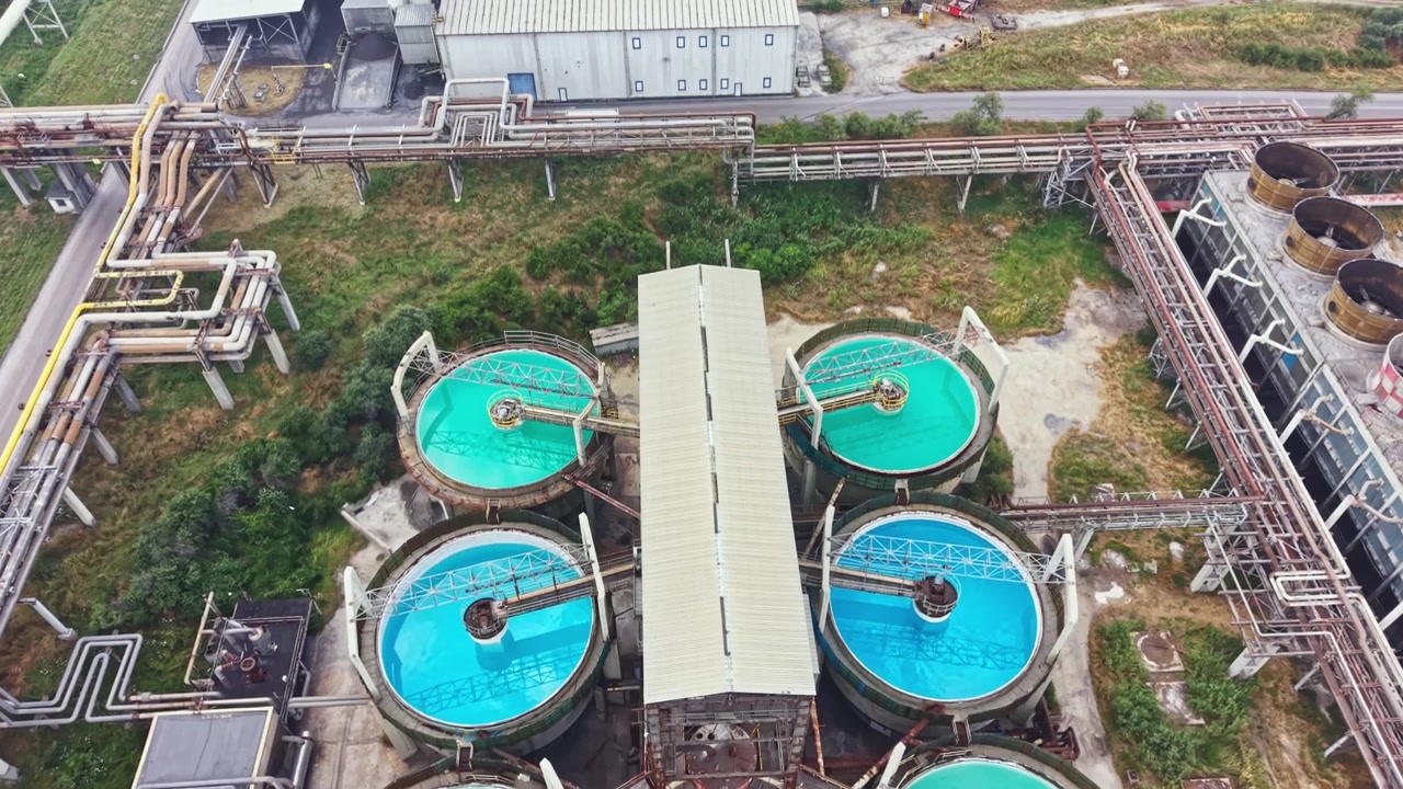 Large water treatment facility in an industrial area with several circular tanks for processing and purifying water