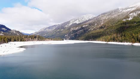 backwards drone footage in 4k of snow capped mountains in lake kachess, washington state