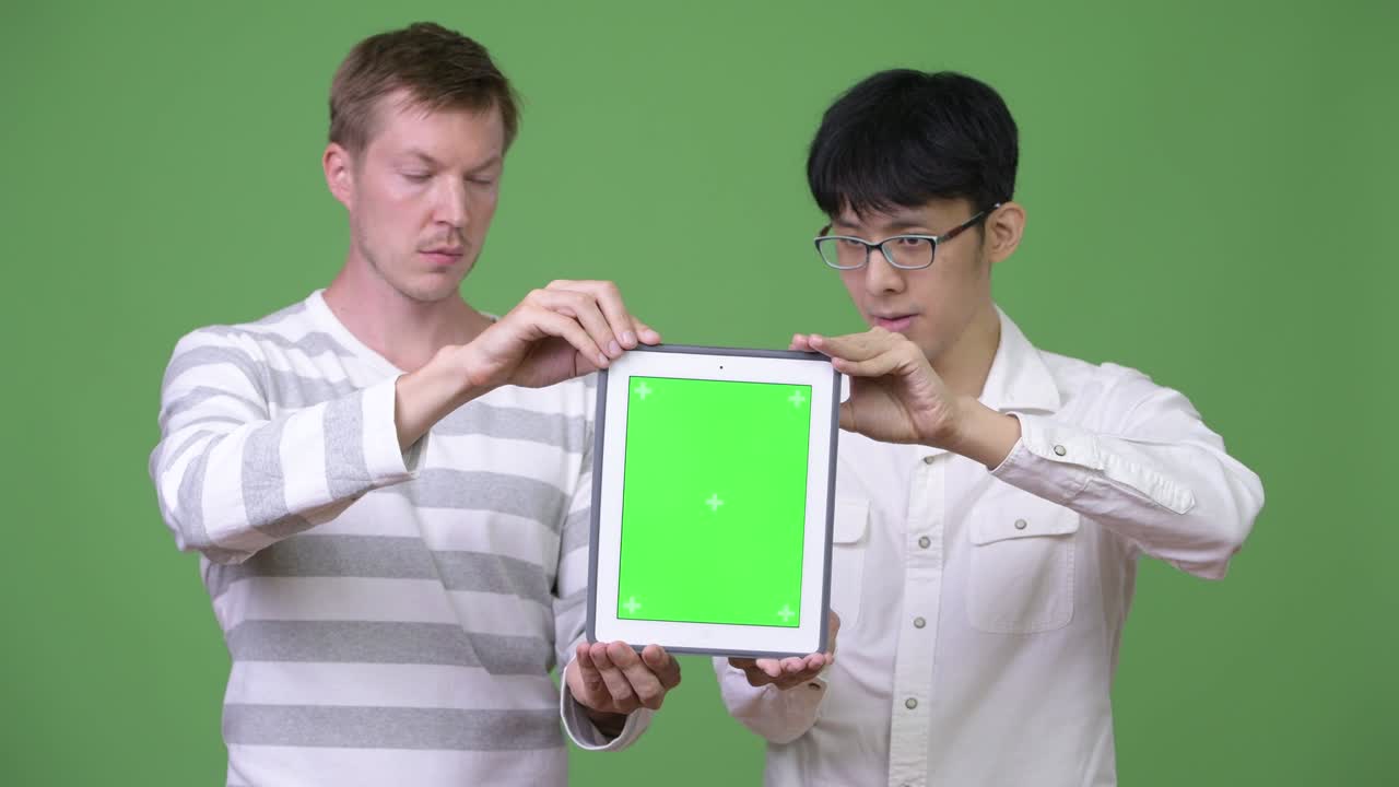 두 명의 젊은 다민족 사업가들이 함께 카메라에 디지털 태블릿을 보여주고 있습니다.