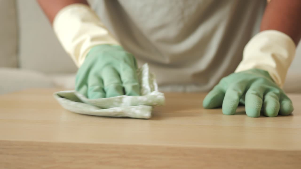 Person in gloves cleaning a wooden surface