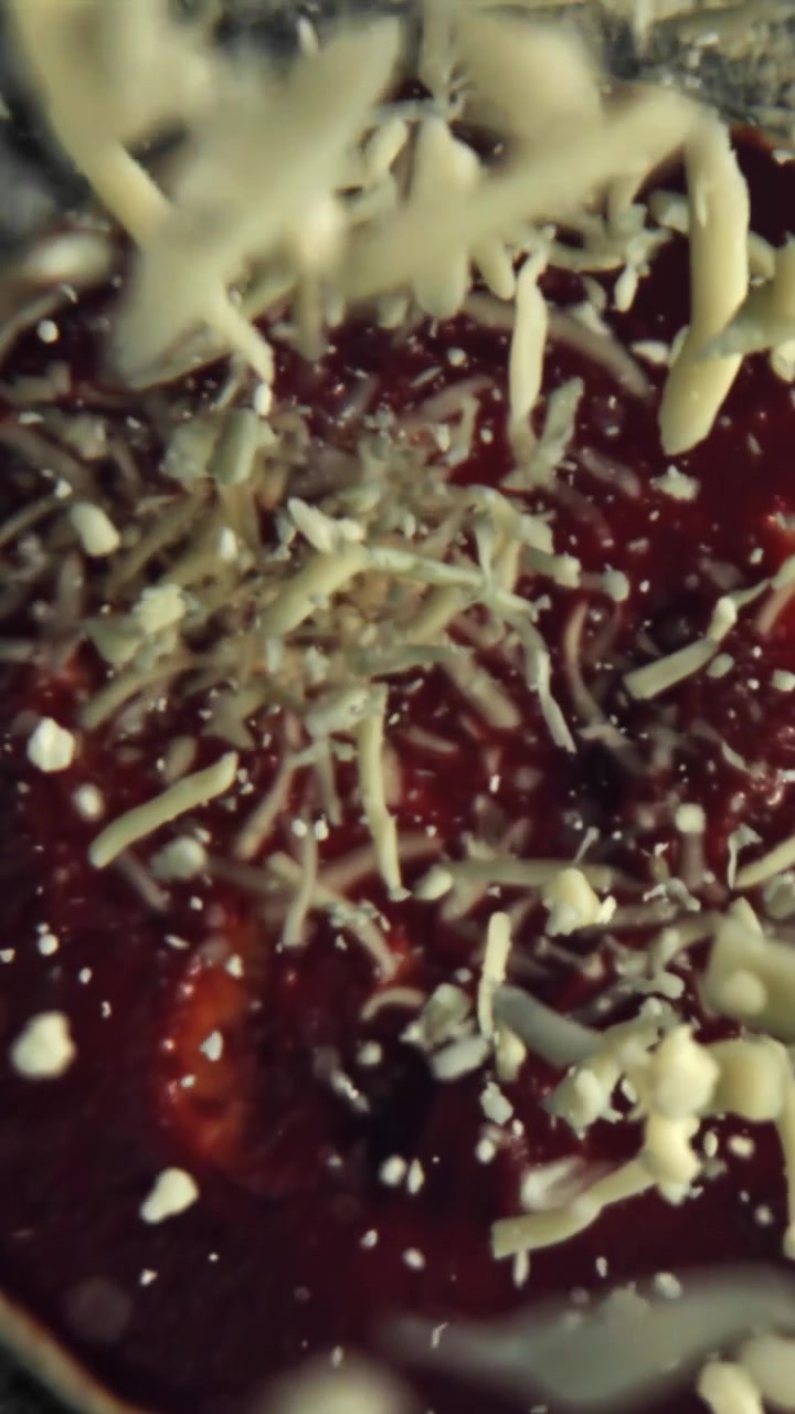 Slow Motion of Shredded Cheese Falling onto Red Pizza Sauce