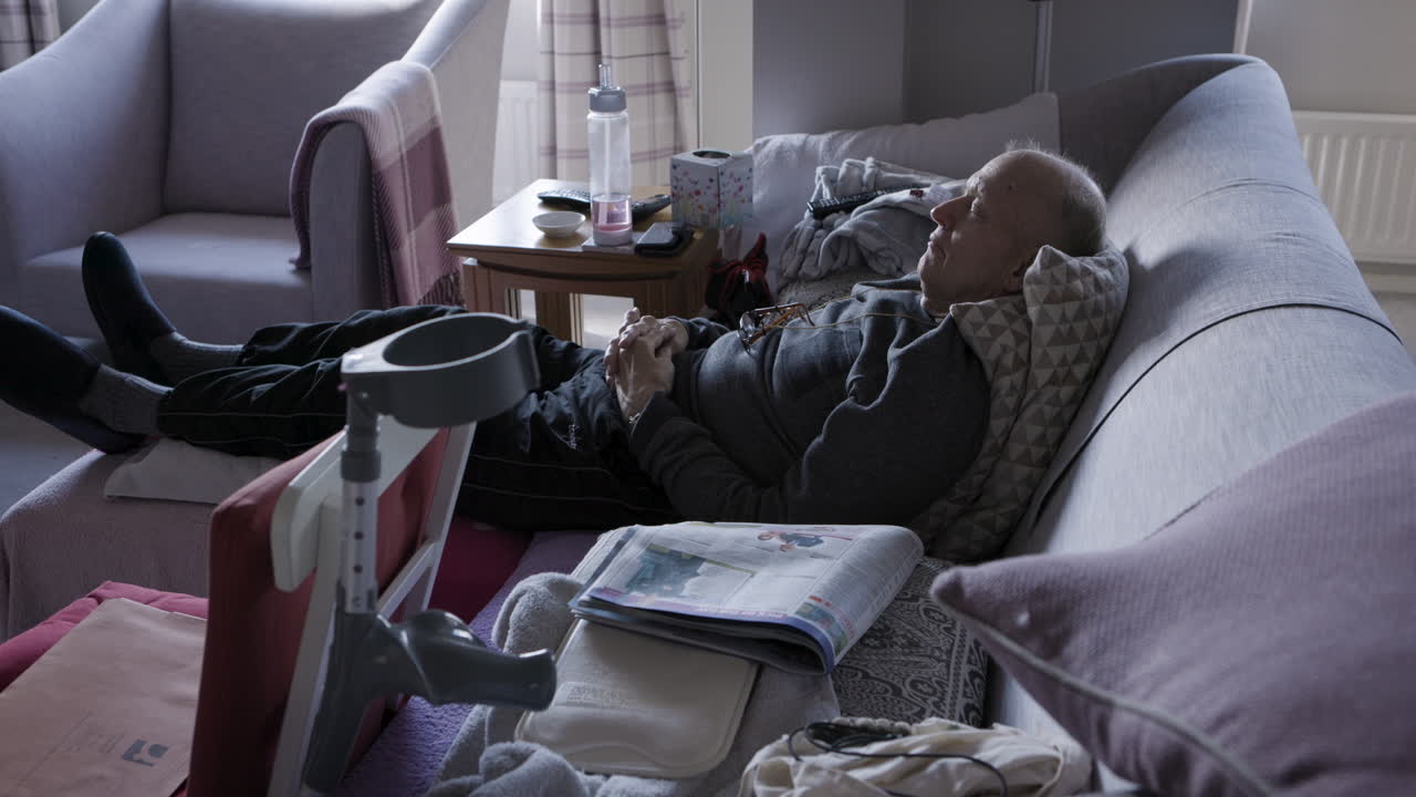 Elderly man resting on couch in living room