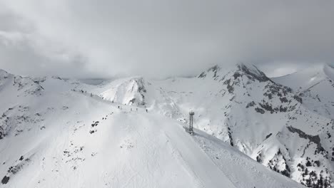 panning slowmotion panoramic drone shot showing a skier riding down the mountainridge