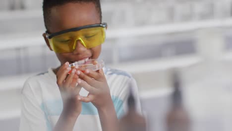 Video-Eines-Glücklichen-Afroamerikanischen-Jungen,-Der-Während-Des-Chemieunterrichts-Eine-Brille-Trägt-Und-Reagenz-In-Der-Hand-Hält