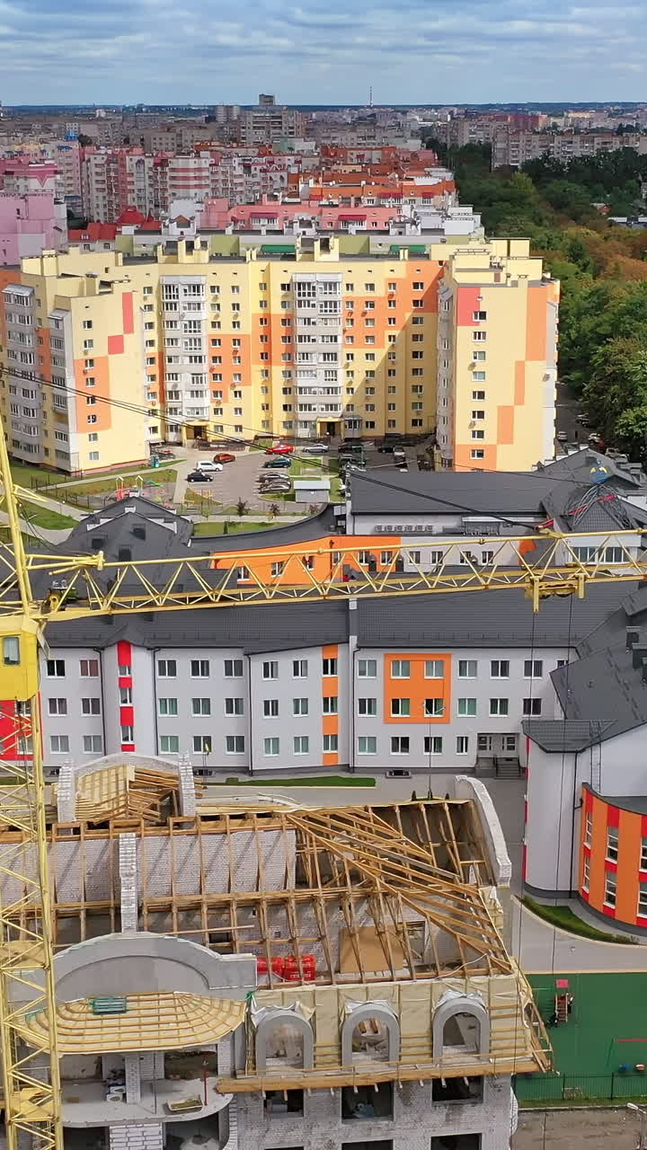 Construction site shot from above. Aerial view of new residential building under construction. High crane at the building Vertical video