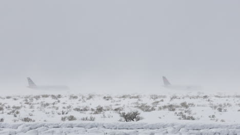 telephoto shot of two airplanes waiting on the tarmac during an intense snow storm in western wyoming. shot in 4k 60fps