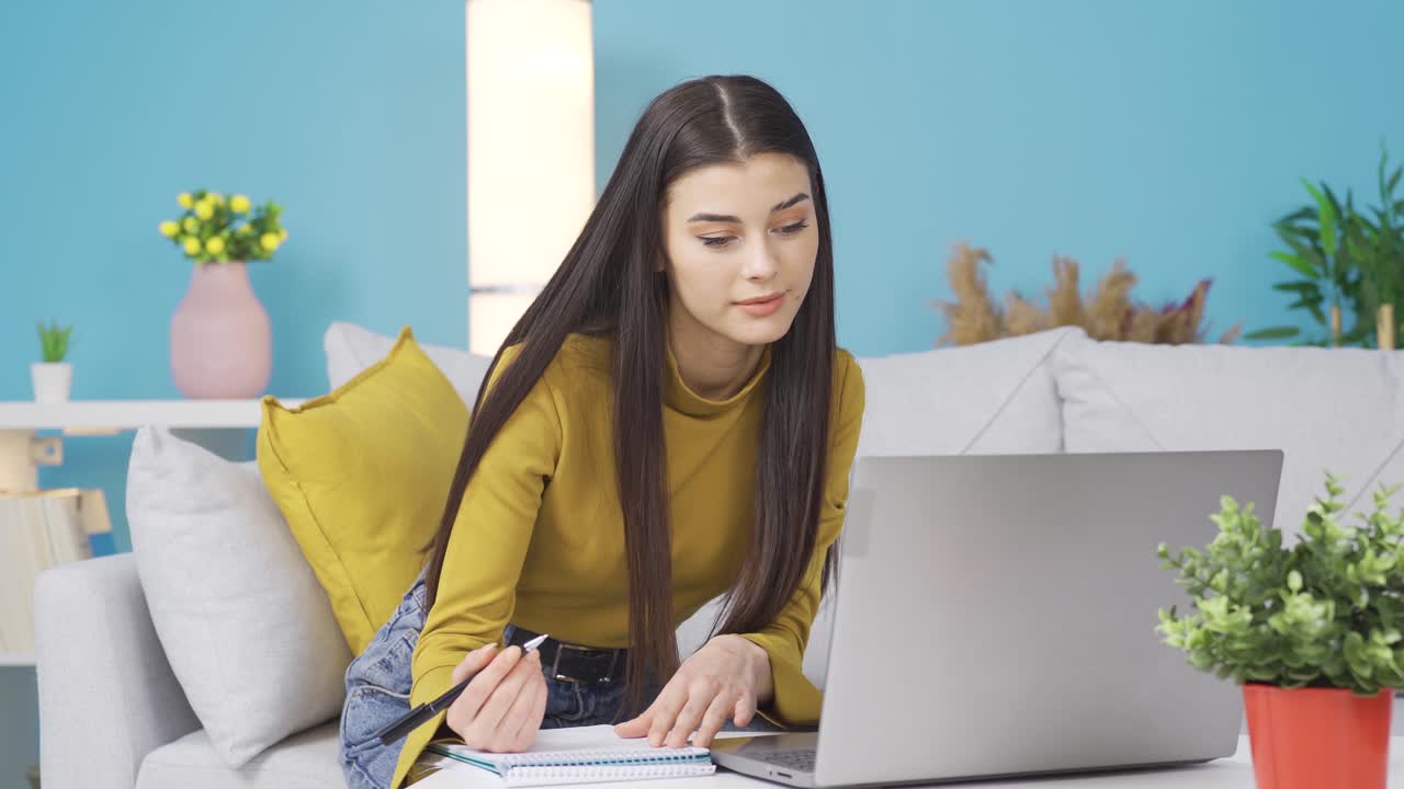 mujer positiva mirando la computadora portátil en casa trabajando, haciendo lista feliz.