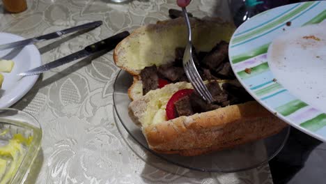 man adding roast beef to deli sandwich