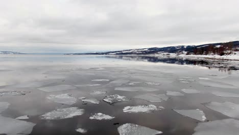 low angle aerial over freezing lake with landscape