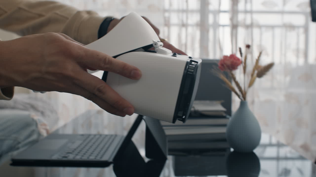 Man writes program on laptop and puts on VR headset while sitting on couch