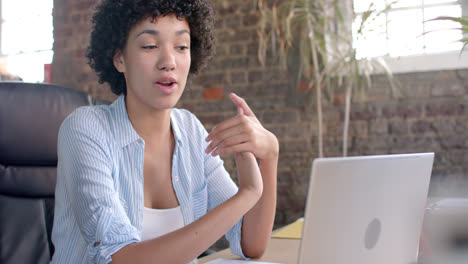 Focused-biracial-casual-businesswoman-having-laptop-video-call-in-office-in-slow-motion